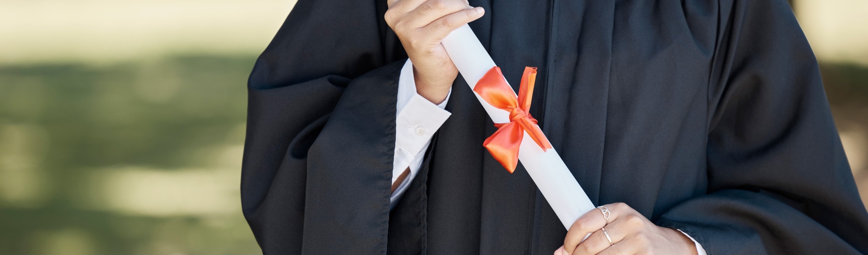Woman in graduation gown holding degree scroll